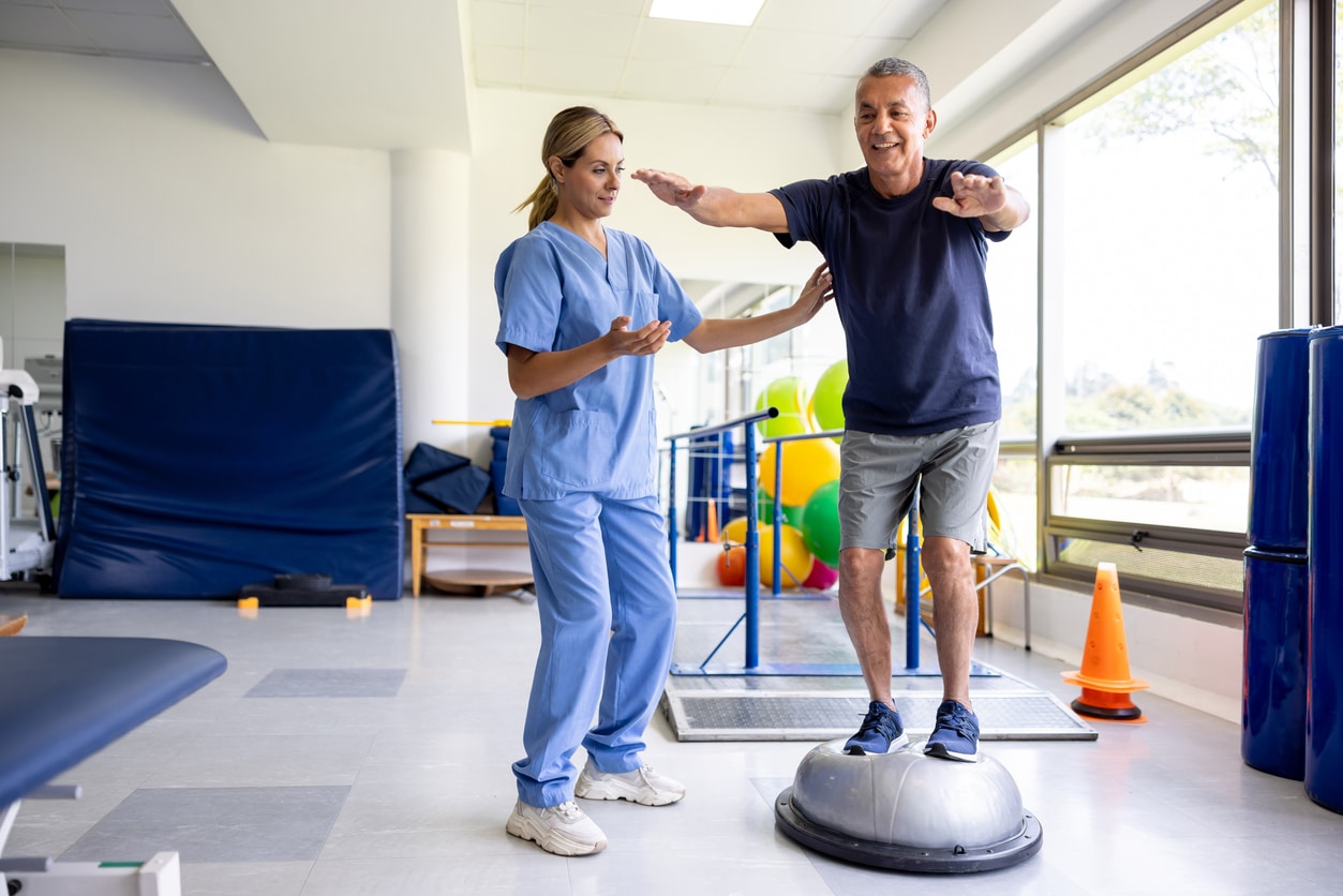 Man doing physical therapy exercises using a balance ball.