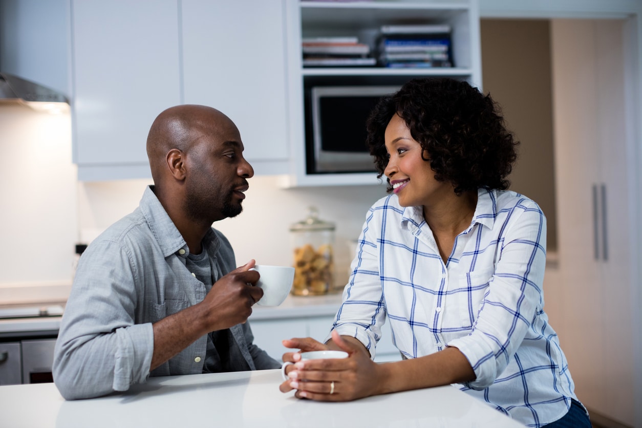 Couple sitting at their kitchen island and talking.